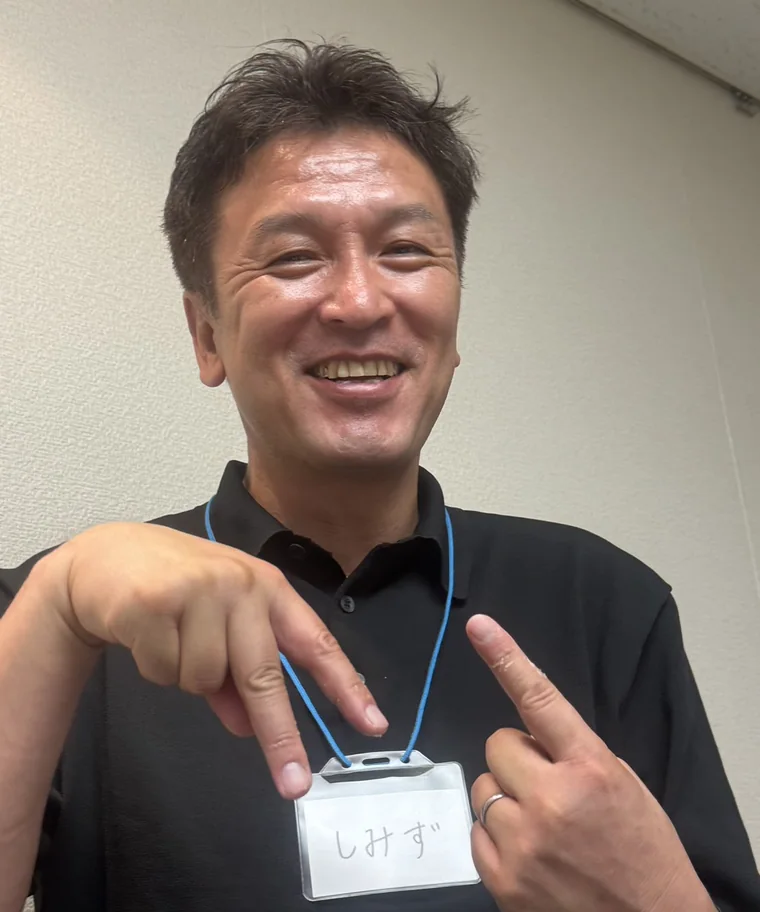 笑顔で指で「AI」をつくる清水 桂太