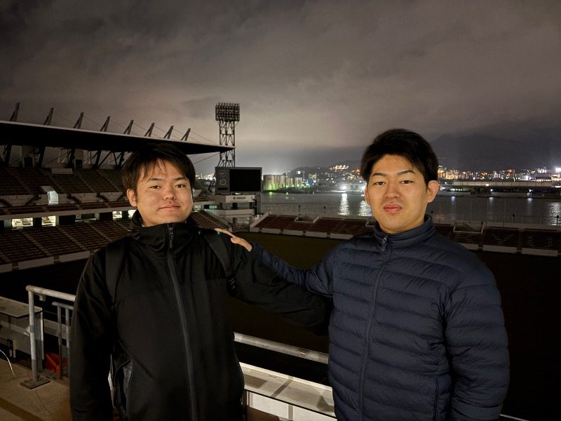 夜のスタジアムを背にした参加者2人
