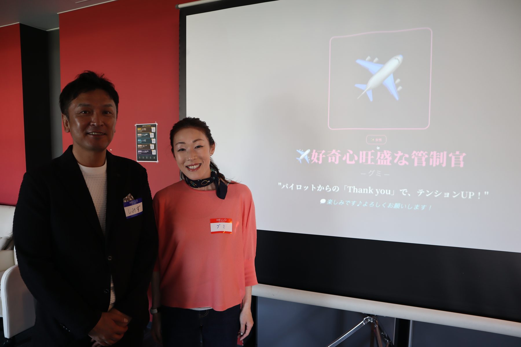 診断結果がスクリーンに映り、その横に本人が立っている