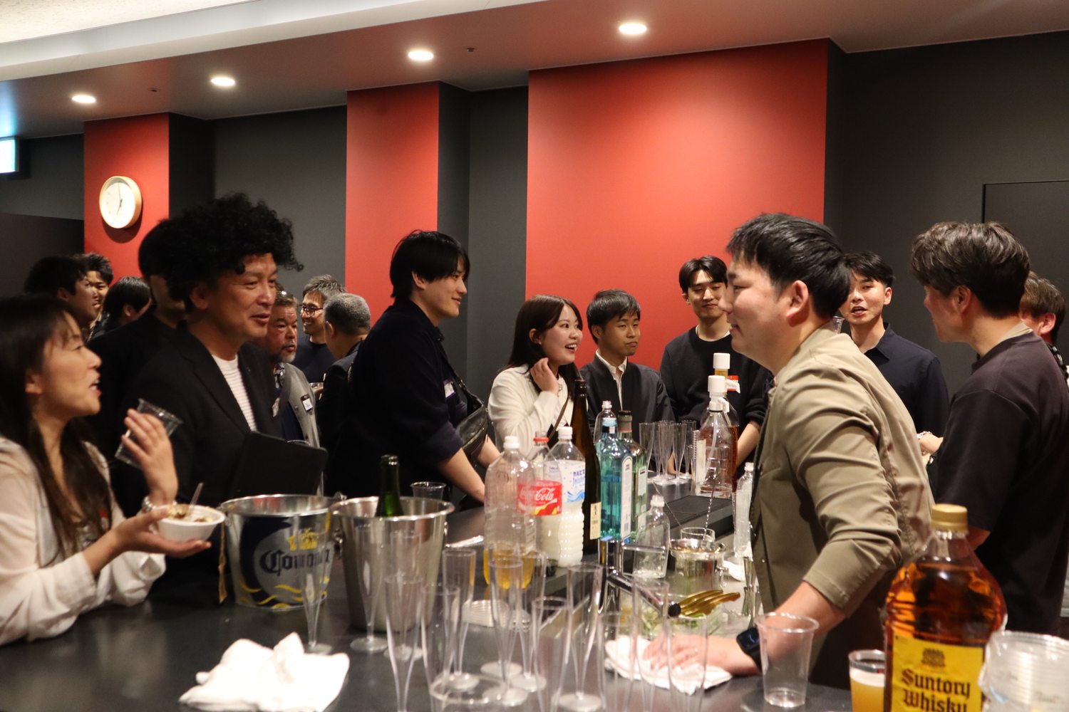 テーブルに並んだお酒と、談笑する参加者